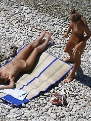 Real naked people revel in sea and sun on the shore